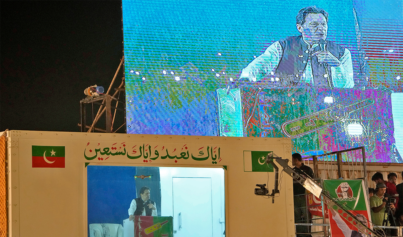 Protected by a bulletproof barrier, former Prime Minister Imran Khan speaks during a rally in Lahore, Pakistan, on March 26, 2023, to pressure the government of Shahbaz Sharif to agree to hold snap elections. (AP)