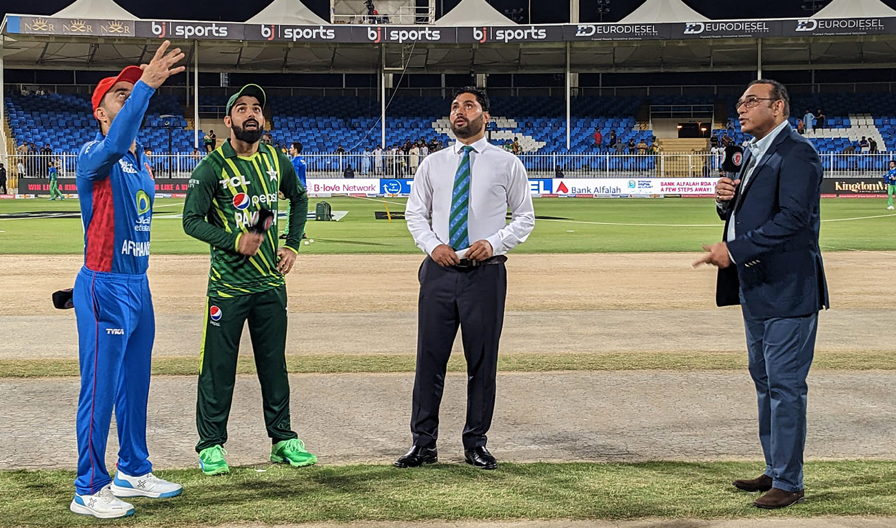 Pakistan's captain Shadab Khan (second left) and his Afghan counterpart Rashid Khan (left) watch the coin during the toss before the start of the second T20 clash of the three-match series between Afghanistan and Pakistan at the Sharjah Cricket Stadium on March 26, 2023. (Photo courtesy: PCB)