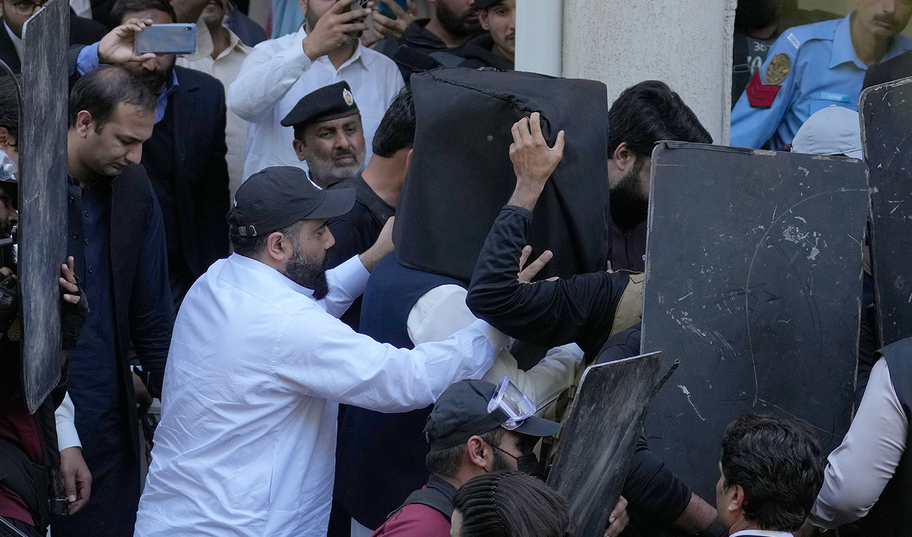 Security personnel with bulletproof shields escort former Prime Minister Imran Khan, center, as he arrives to appear in a court, in Islamabad, Pakistan, Monday, March 27, 2023. (Photo courtesy: AP)