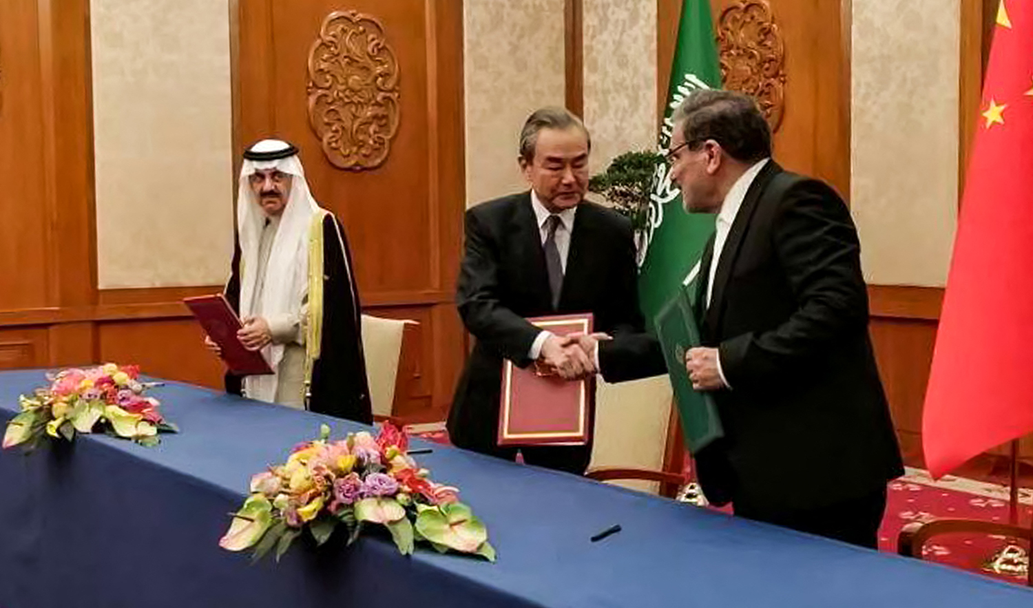 Secretary of the Supreme National Security Council of Iran Ali Shamkhani, right, shakes hands with the Director of the Office of the Central Foreign Affairs Commission of the Chinese Communist Party (CCP) Wang Yi, center, during a meeting with Saudi Arabia's National Security adviser Musaad bin Mohammed al-Aiban in Beijing on March 10, 2023. (AFP via Nournews agency)