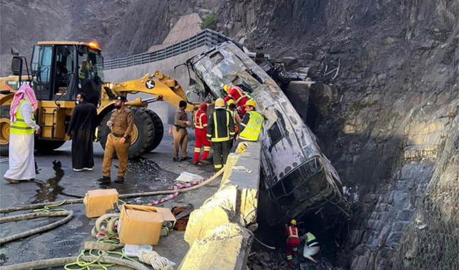 Police and rescue officials inspect a burnt-out passenger bus at the crash site in the Asir region, Saudi Arabia on March 27, 2023. (Photo courtesy: Al Arabiya)
