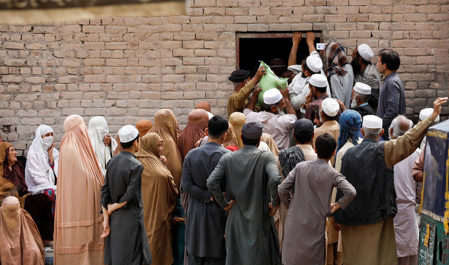 People gather to receive sacks of free flour, at a distribution point in Peshawar, Pakistan on March 30, 2023. (REUTERS)