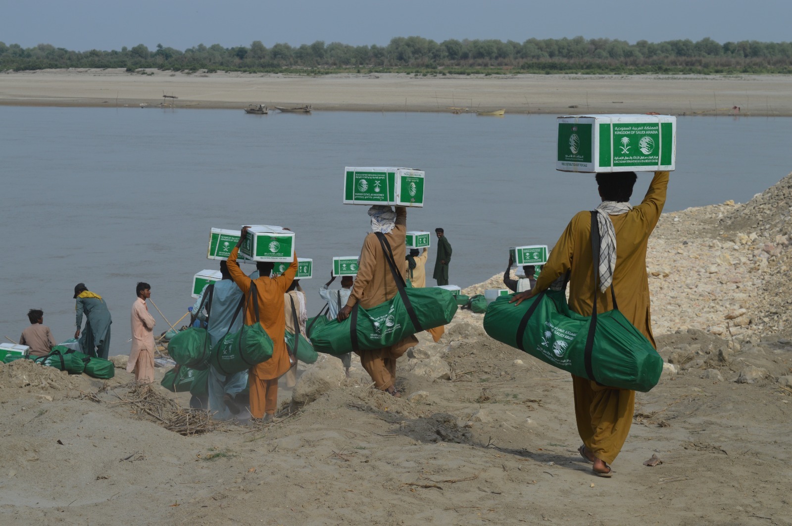 Flood-affected Pakistanis carrying aid distrubuted by Saudi Arabia's King Salman Humanitarian Aid and Relief Center (KSrelief) on March 30, 2023. (Photo courtesy KSrelief)
