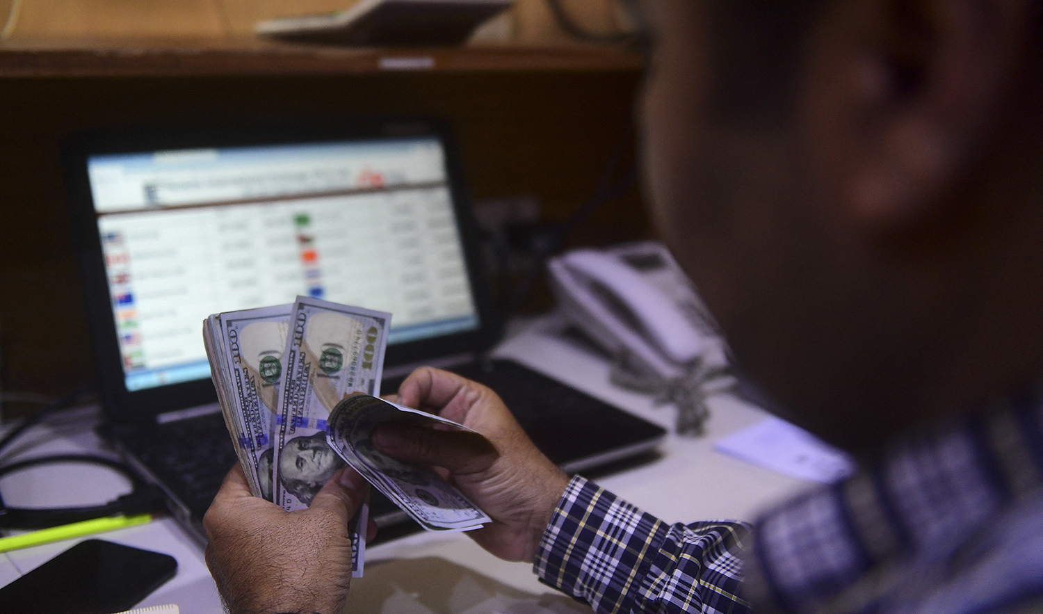 A dealer counts US dollars at a money exchange market in Karachi, Pakistan on March 2, 2023. (AFP)