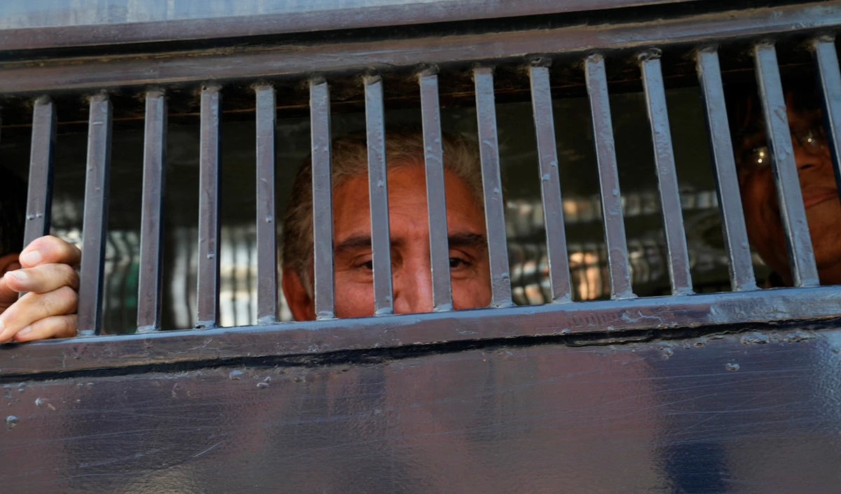 Shah Mahmood Qureshi, left, and Asad Omar, senior leaders of Pakistan's former prime minister Imran Khan's 'Pakistan Tehreek-e-Insaf' party look to media from inside a police van during a rally in Lahore on February 22, 2023. (AP)
