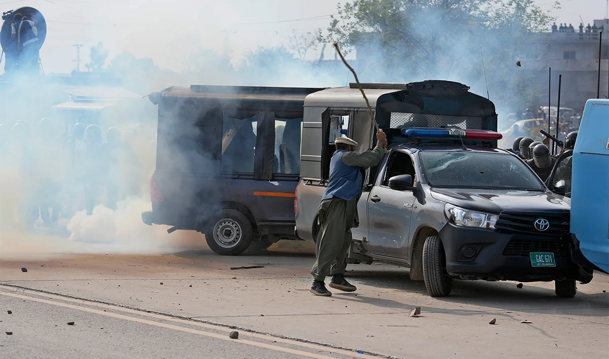 A supporter of former Prime Minister Imran Khan damage a police vehicle as police fire tear gas to disperse them during clashes, in Islamabad, Pakistan, Saturday, March 18, 2023. (AP)