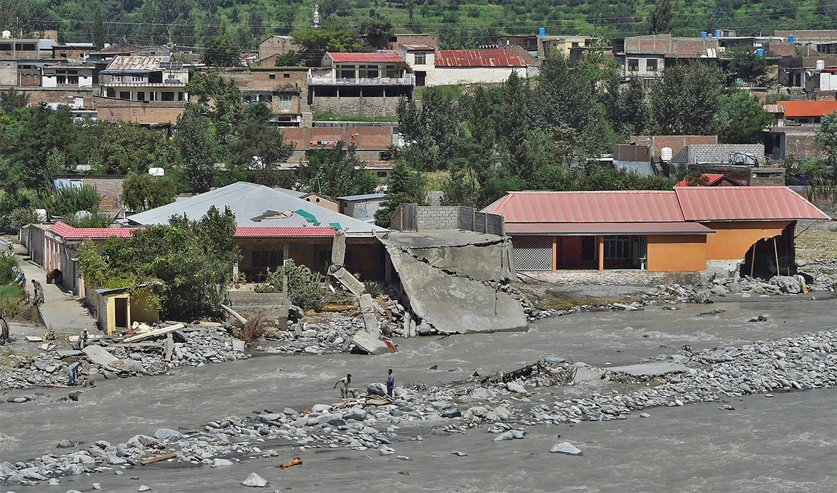 Local residents stand near houses damaged along the banks of the Swat River after heavy rains in Madyan area of Swat valley, Khyber Pakhtunkhwa province, on August 31, 2022. (AFP/File)