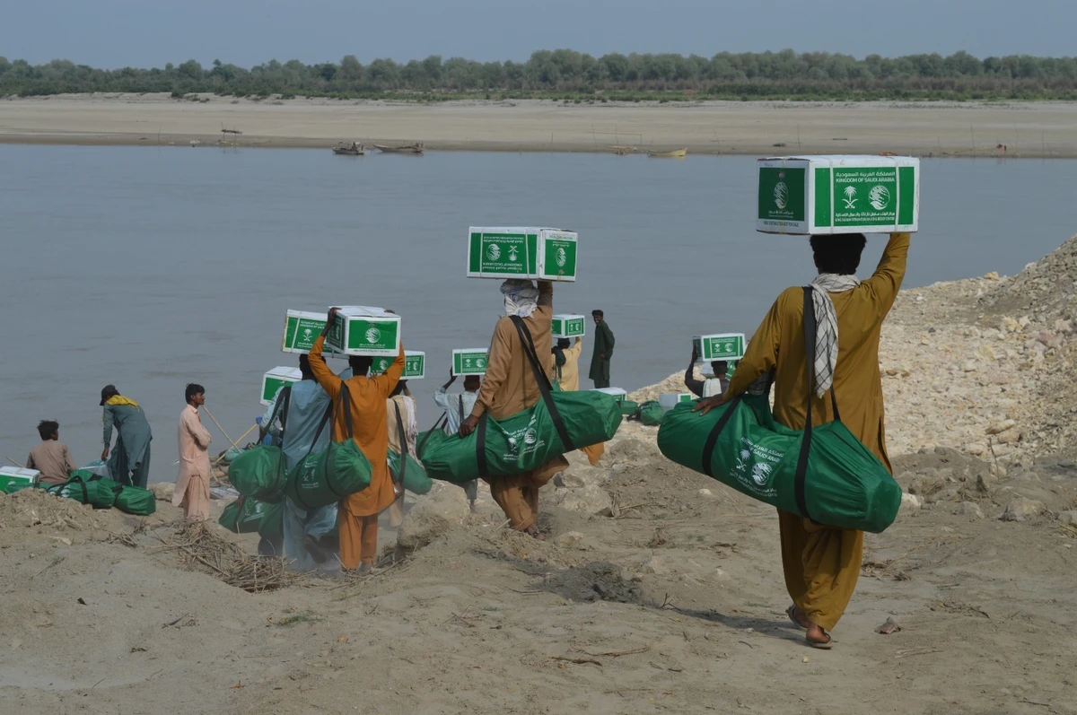 Flood-affected Pakistanis carrying aid distrubuted by Saudi Arabia's King Salman Humanitarian Aid and Relief Center (KSrelief) on March 30, 2023. (Photo courtesy KSrelief)