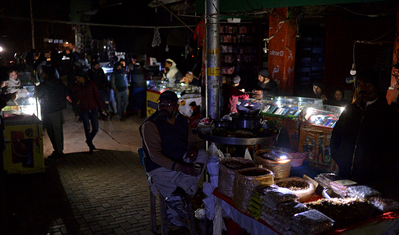 Shopkeepers sit at a market during a nationwide power outage, in Islamabad on January 23, 2023. (AFP/File)