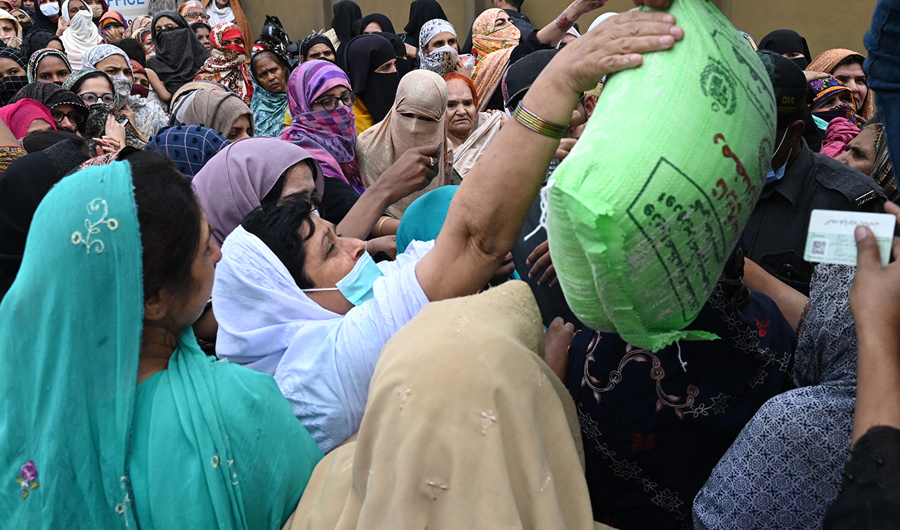 People gather to receive the free bags of flour from a delivery truck at a distribution point ahead of the Muslim holy fasting month of Ramadan, in Lahore on March 20, 2023, following an announcement from Pakistan’s Prime Minister Shehbaz Sharif to provide free flour to the needy people during the Ramadan in the wake of country's soaring inflation. (AFP/File)