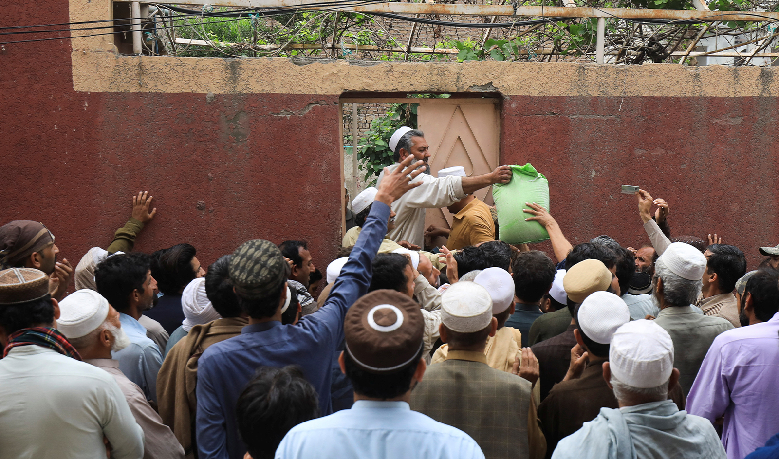 People gather to receive sacks of free flour at a distribution point in Peshawar, Pakistan, on March 30, 2023. (REUTERS)