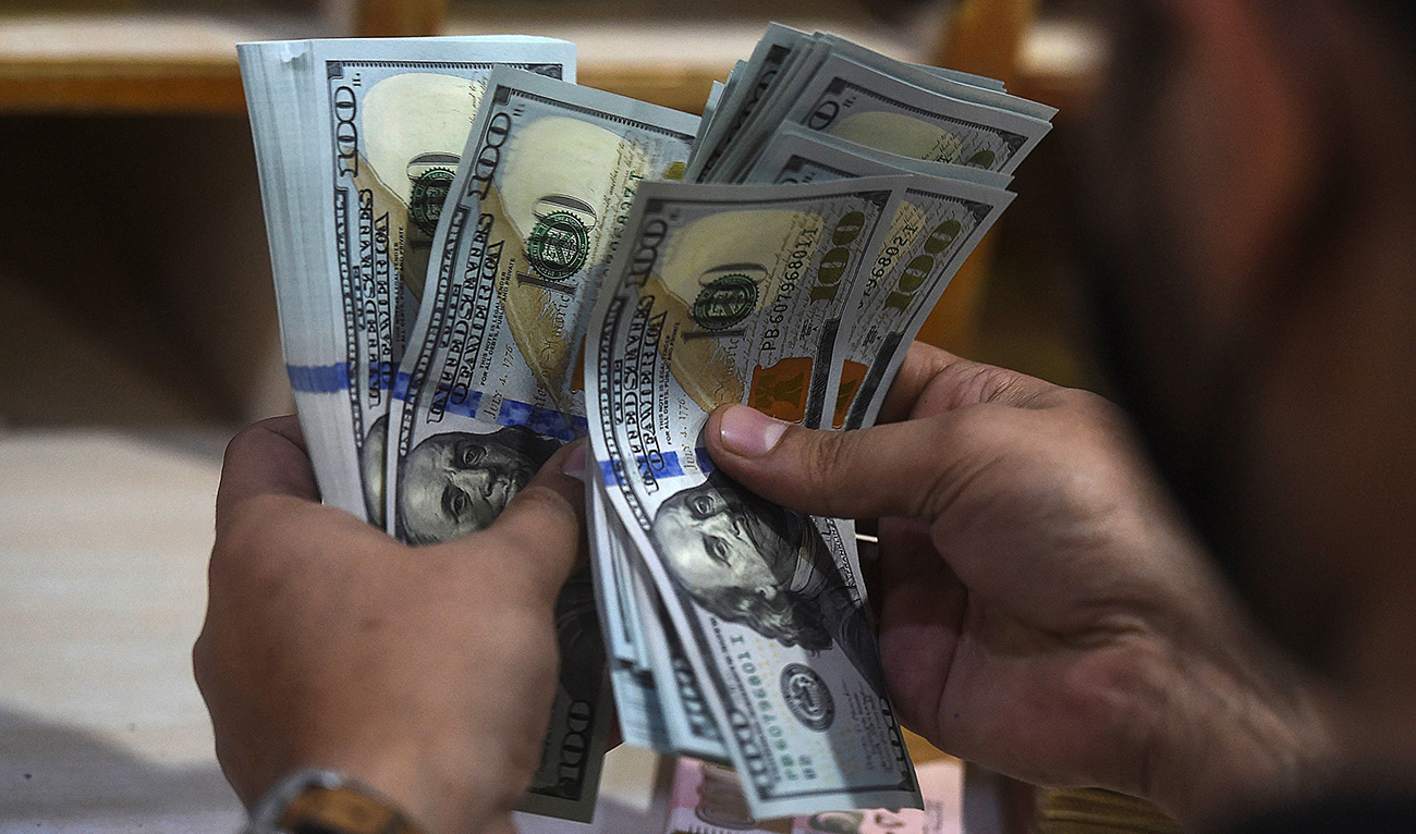 In this picture taken on January 11, 2022, a foreign currency dealer counts US dollar notes at a shop in Karachi. Pakistan's inflation hit about 10 percent last year, according to the World Bank, with cooking oil prices up 130 percent since Prime Minister Imran Khan took power, as well as the cost of fuel up 45 percent.
