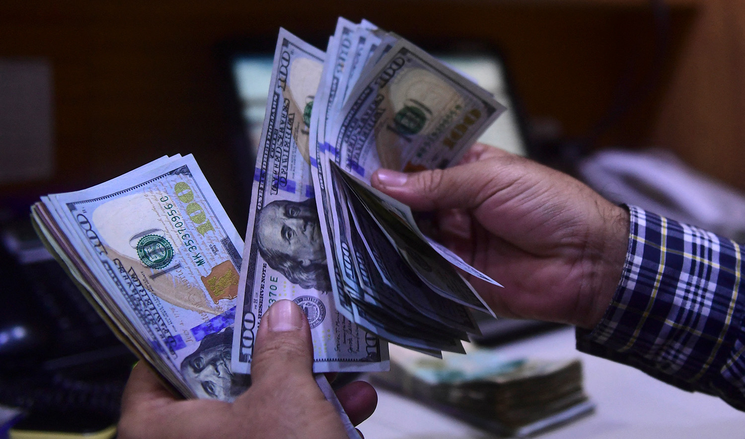 A dealer counts US dollars at a money exchange market in Karachi, Pakistan on March 2, 2023. (AFP)