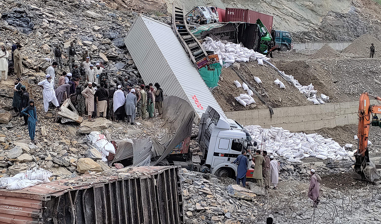 Security officials and onlookers gather near damaged trucks following a landside near Pakistan's Torkham border town on April 18, 2023. (Photo courtesy: AFP)