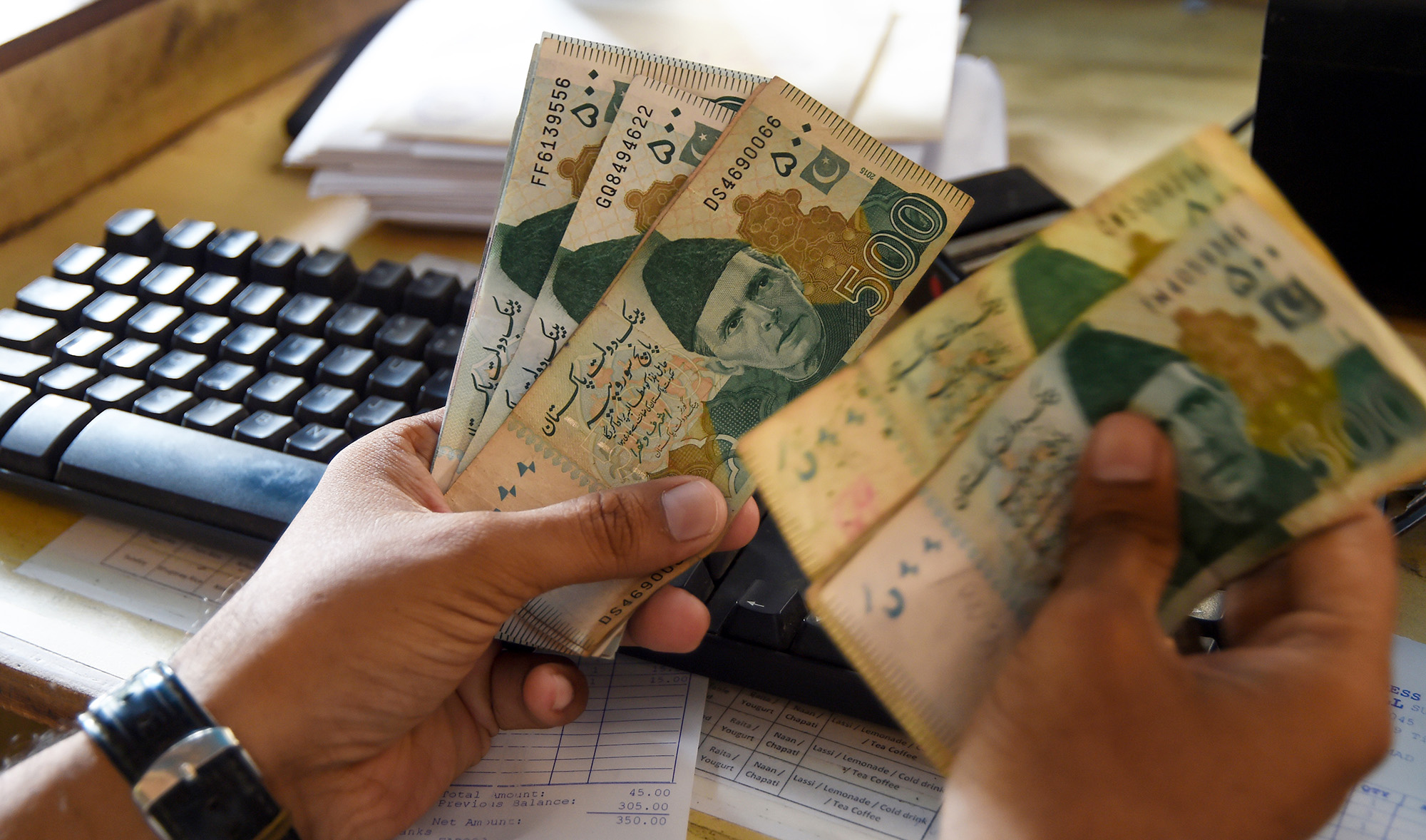 A Pakistani man counts Pakistan's rupees at his shop in Karachi on May 16, 2019. (AFP/File)
