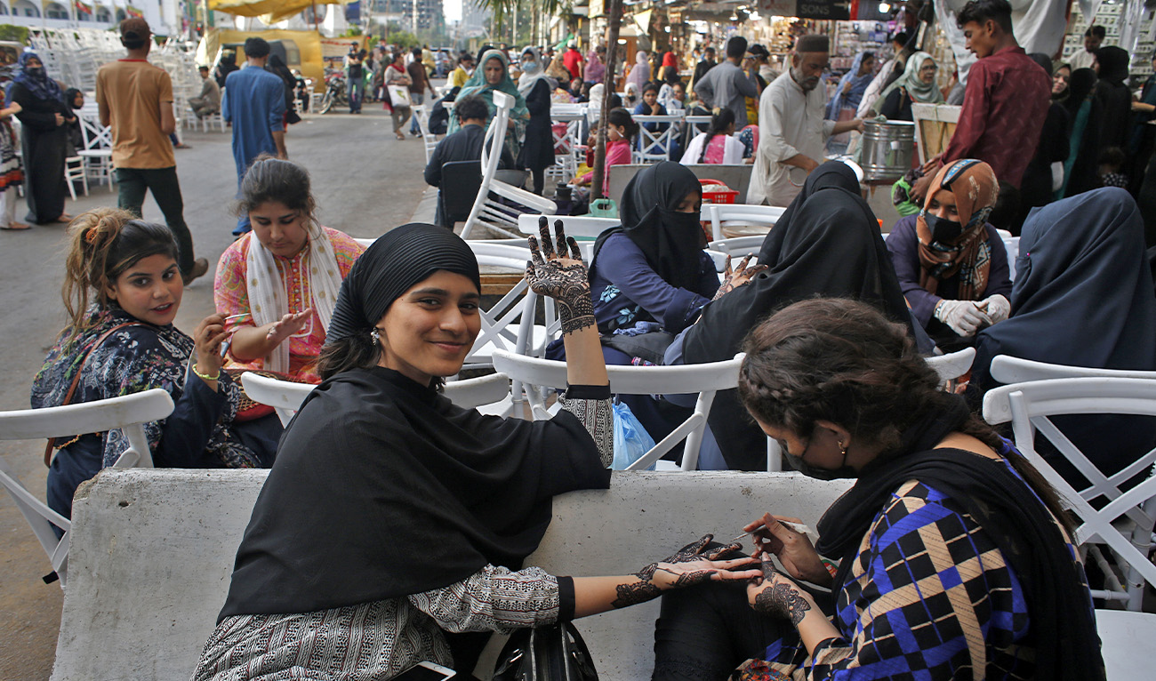A girl looks into the camera as a henna artist applies henna designs on her in Gulf Market ahead of the Eid al-Fitr festival, which marks the end of the holy fasting month of Ramadan, in Karachi, Pakistan, on April 20, 2023. (AN photo)
