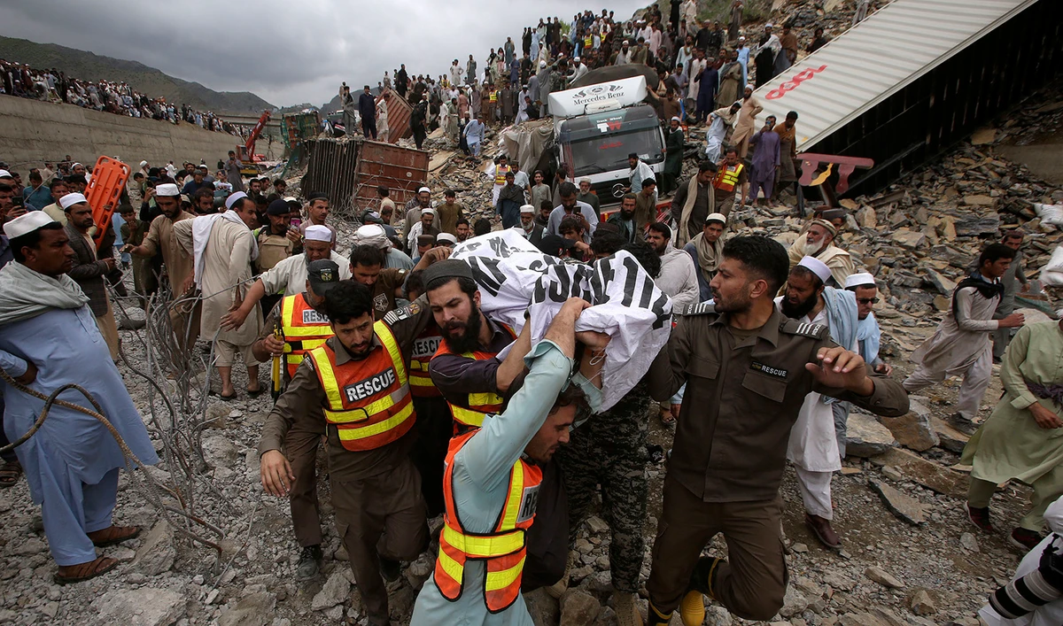 Rescue workers and volunteers carry a body recovered from the rubble at the site of landslide near the Torkham border town of Pakistan, on April 18, 2023. (AP)