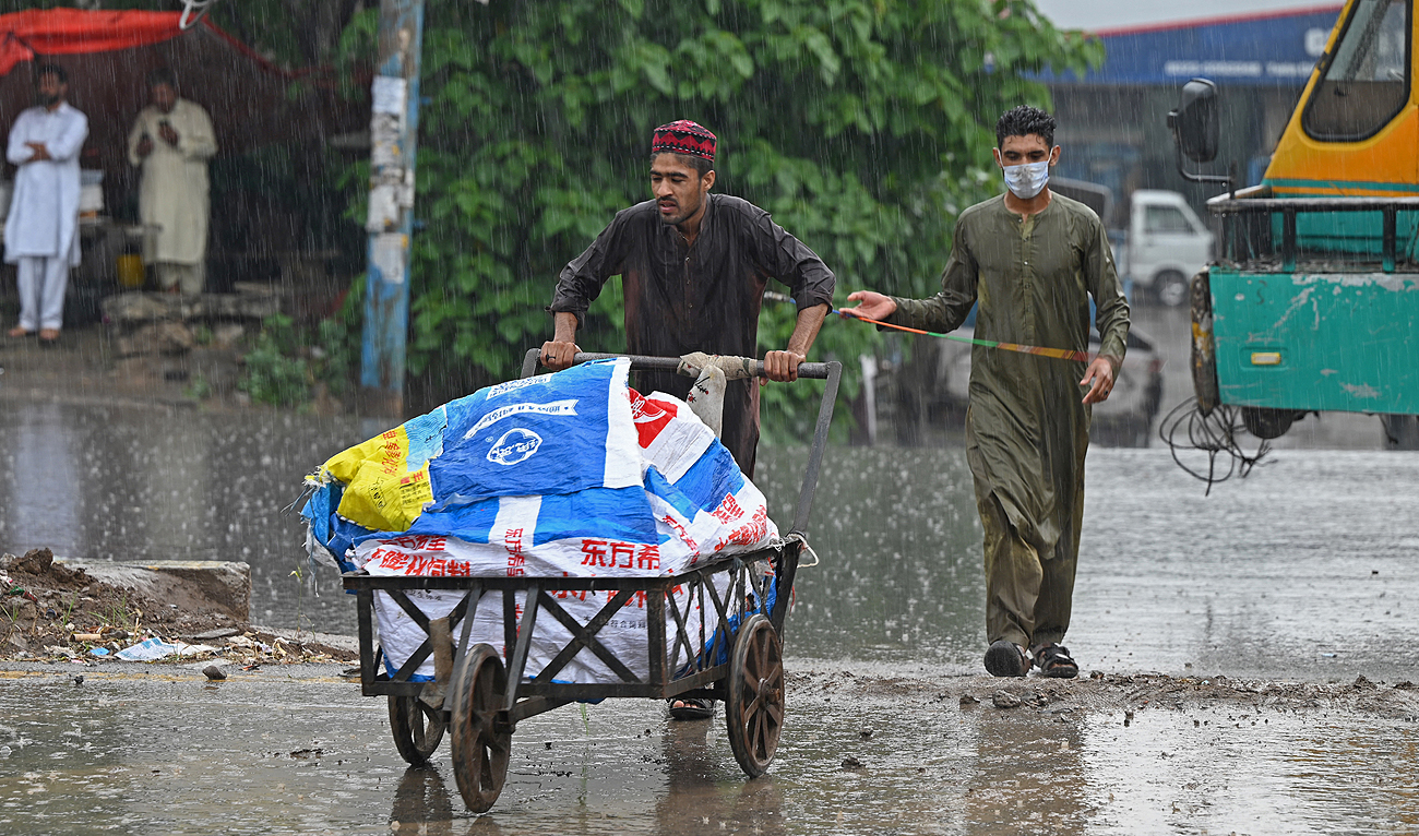 A man pushes a handcart along a street as it rains in Rawalpindi on May 1, 2023. (AFP)