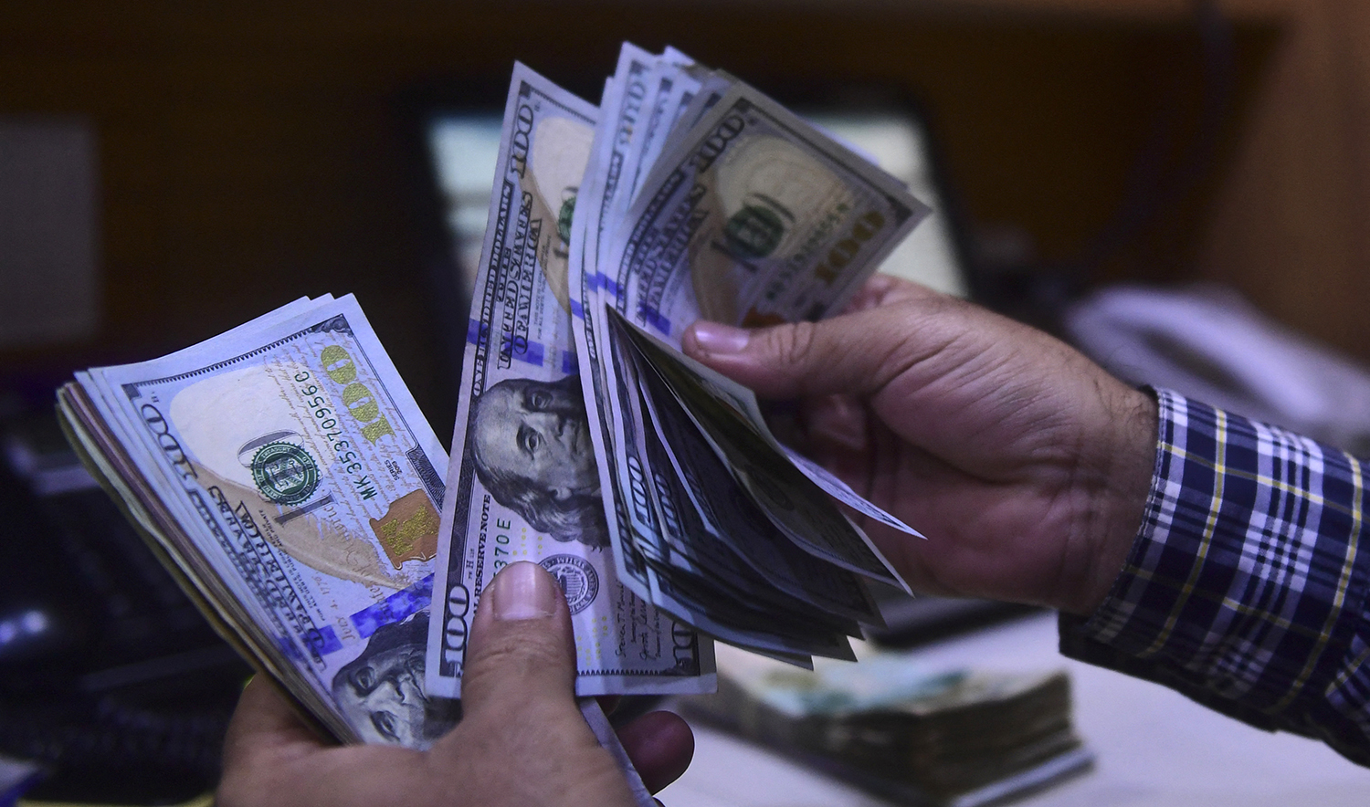 A dealer counts US dollars at a money exchange market in Karachi, Pakistan on March 2, 2023. (AFP/File)