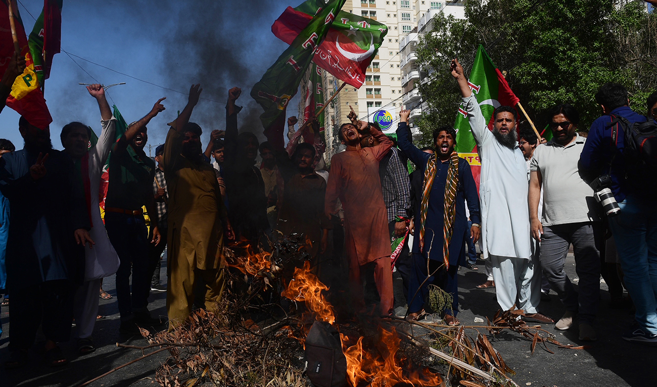 Pakistan Tehreek-e-Insaf party activists and supporters of former Pakistan's Prime Minister Imran shout slogans next to a fire as they block a road during a protest against the arrest of their leader in Karachi on May 9, 2023.
