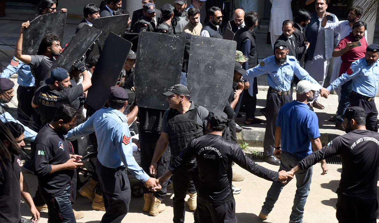 Private security personnel with bulletproof shields escort former Prime Minister Imran Khan as he arrives to appear in a court, in Islamabad, Pakistan, on May 9, 2023. (AP)