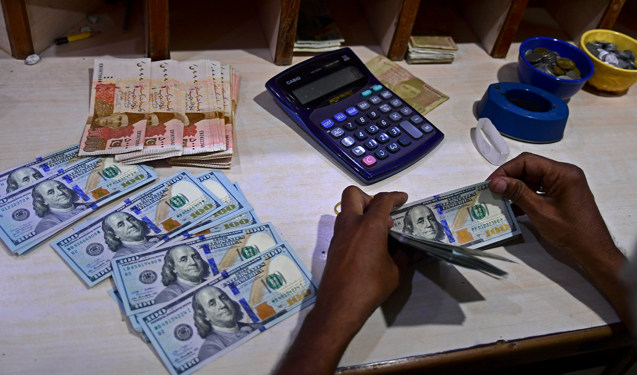 A foreign currency dealer counts US dollar notes at a currency market in Karachi on July 19, 2022. (AFP/File)