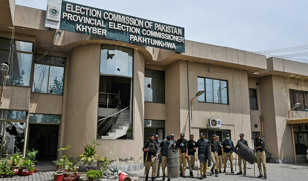 Security personnel stand guard inside an Election Commission of Pakistan building damaged during a protest by Pakistan Tehreek-e-Insaf (PTI) party activists and supporters of former Pakistan's Prime Minister Imran over the arrest of their leader, in Peshawar on May 11, 2023. (AFP)