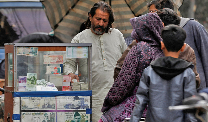A currency broker stands near his booth, which is decorated with pictures of currency notes, while dealing with customers, along a road in Karachi, Pakistan on January 27, 2023. (REUTERS/File)