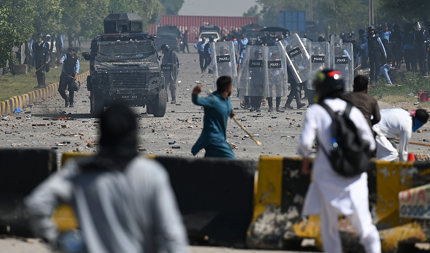 Pakistan Tehreek-e-Insaf (PTI) party activists and supporters (foreground) of former Pakistan's Prime Minister Imran Khan clash with police during a protest against the arrest of their leader, in Islamabad on May 10, 2023. (AFP)