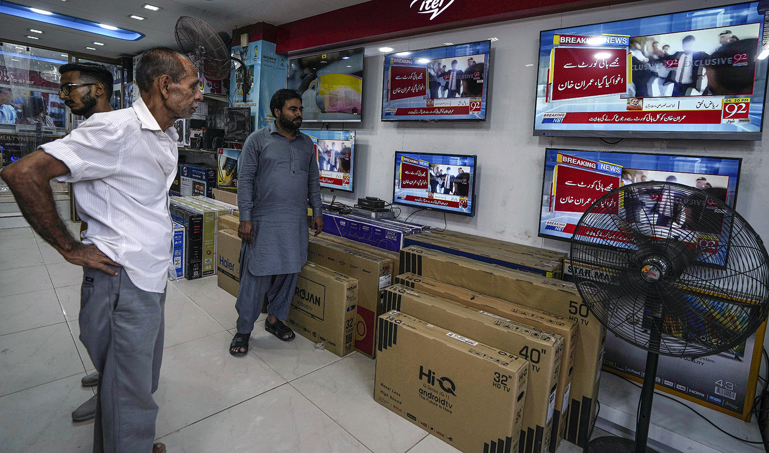 People watch local news channels telecasting news about Pakistan's former Prime Minister Imran Khan at an electronic shop, in Karachi, Pakistan, on May 11, 2023. (AP)