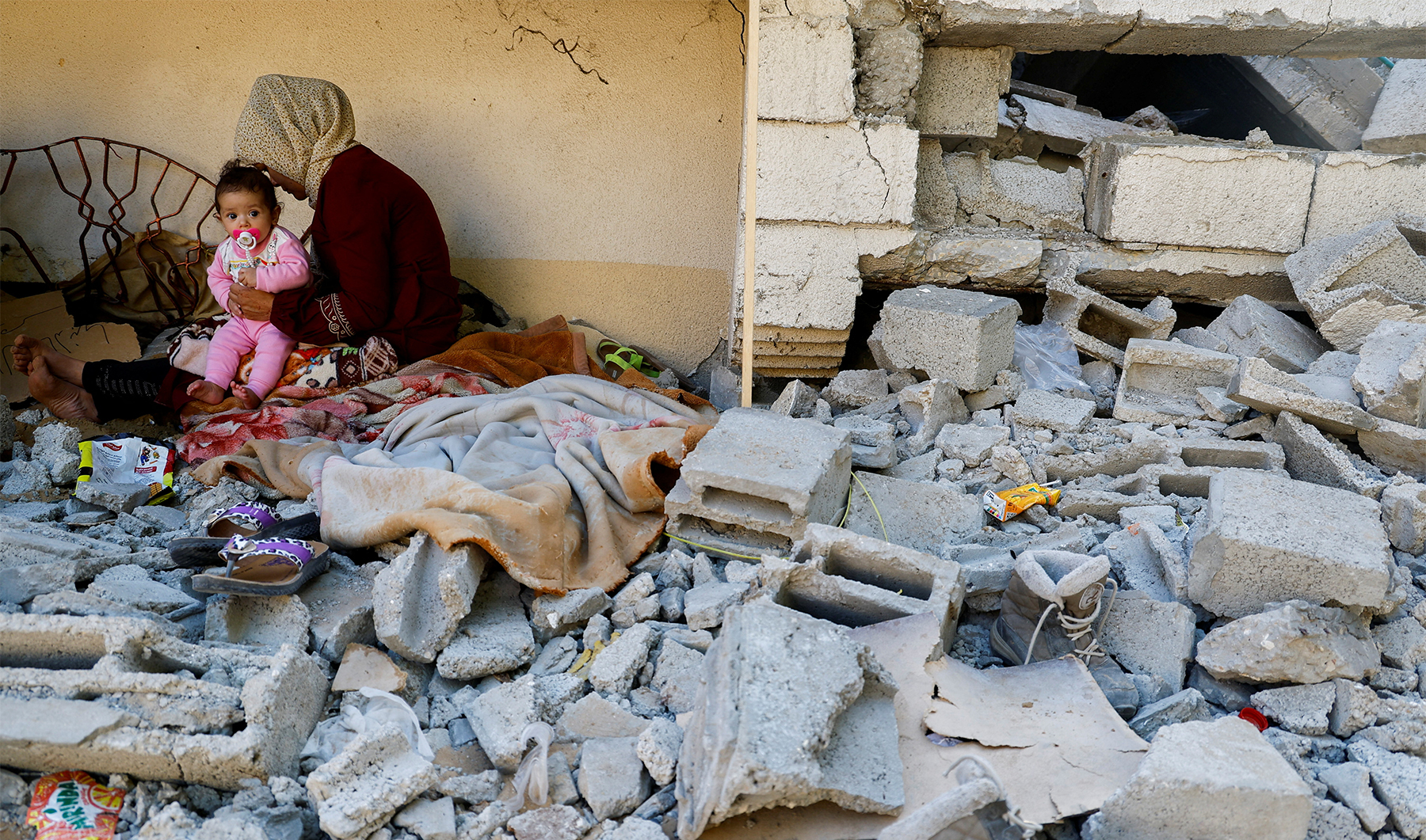 A Palestinian woman sits with her daughter outside their house, which was destroyed by Israeli air strikes during recent fighting between Israel-Gaza, after a ceasefire between Israel and Palestinian factions was agreed, in the northern Gaza Strip, on May 15, 2023. (REUTERS)