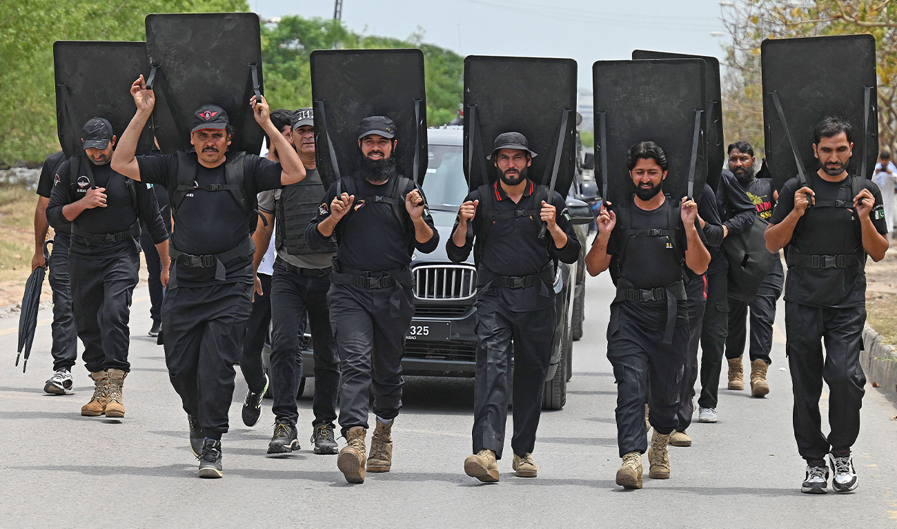 Security personnel with ballistic shields escort a vehicle carrying former Pakistan's prime minister Imran Khan as he leaves after appearing before an anti-terrorism court in Islamabad on May 23, 2023. (AFP)