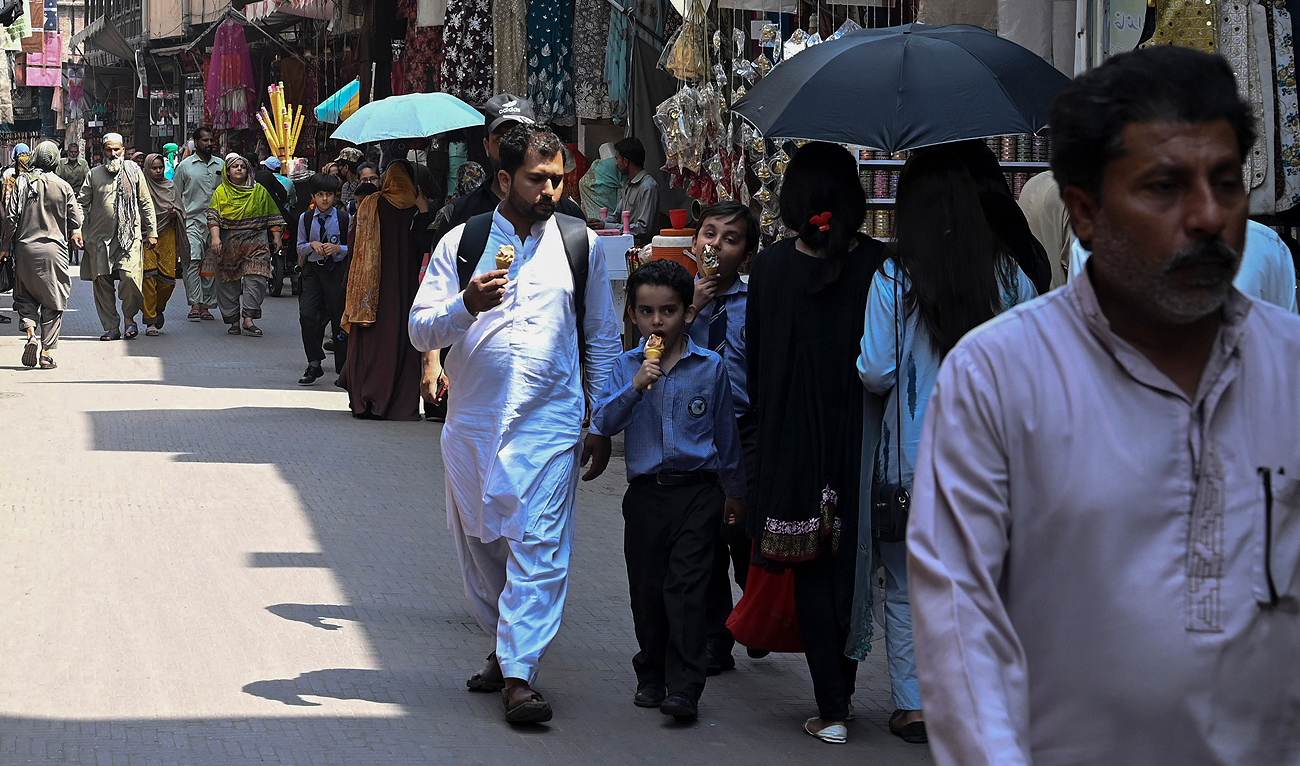 People walk along a market in Lahore on May 17, 2023. (Photo courtesy: AFP)