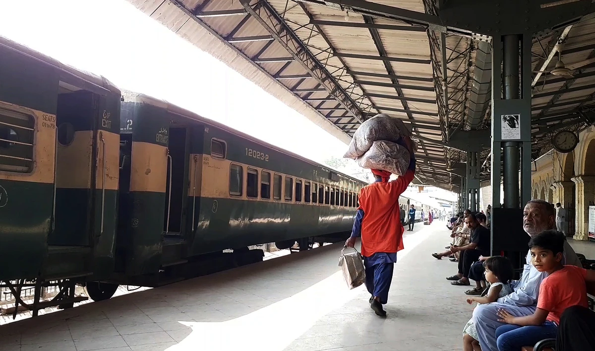 In this picture, taken on November 28, 2022, Pakistan Railway's porter walks past a passenger train at Karachi Cantt Station in Karachi. (Photo courtesy: AN Photo/Rana Malhi)