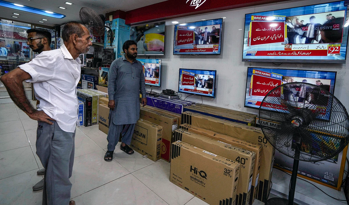 People watch local news channels telecasting news about Pakistan's former Prime Minister Imran Khan at an electronic shop, in Karachi, Pakistan, on May 11, 2023. (AP)