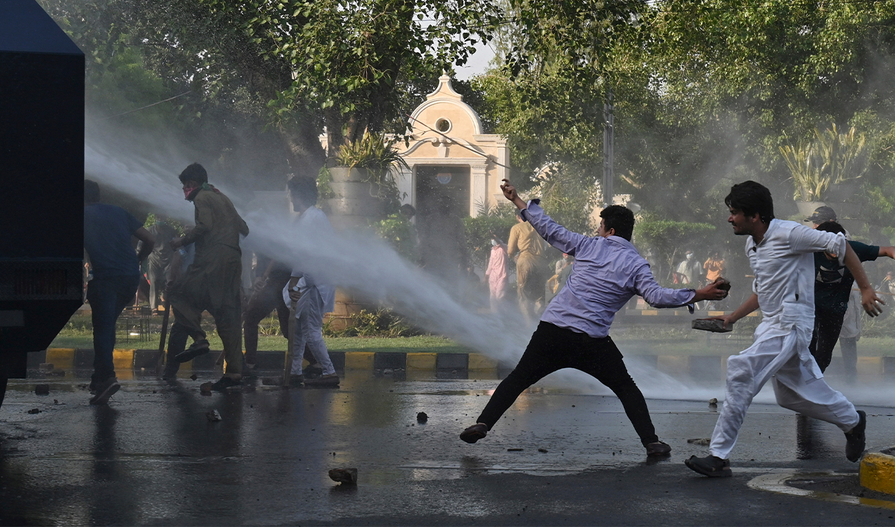 Pakistan Tehreek-e-Insaf (PTI) party activists and supporters of former Pakistan's Prime Minister Imran throw stones to a police water cannon vehicle during a protest against the arrest of their leader, in Lahore, Pakistan, on May 9, 2023. (AFP/File)