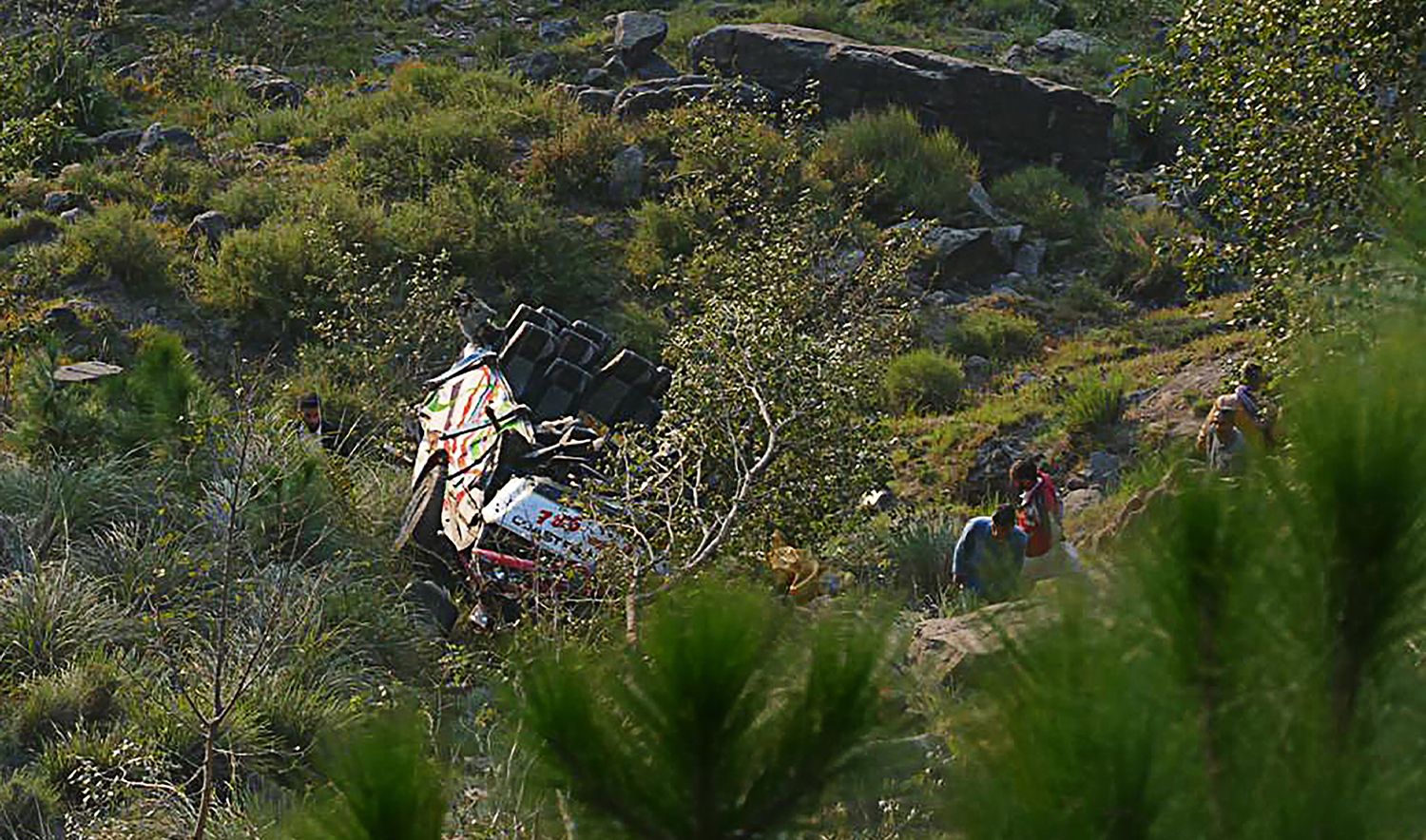 People gather near the wreckage of a passenger bus plunged into a ravine in Pallandri, some 160 km east of Muzaffarabad, the capital of Azad Kashmir, on November 3, 2021. (AFP/File)