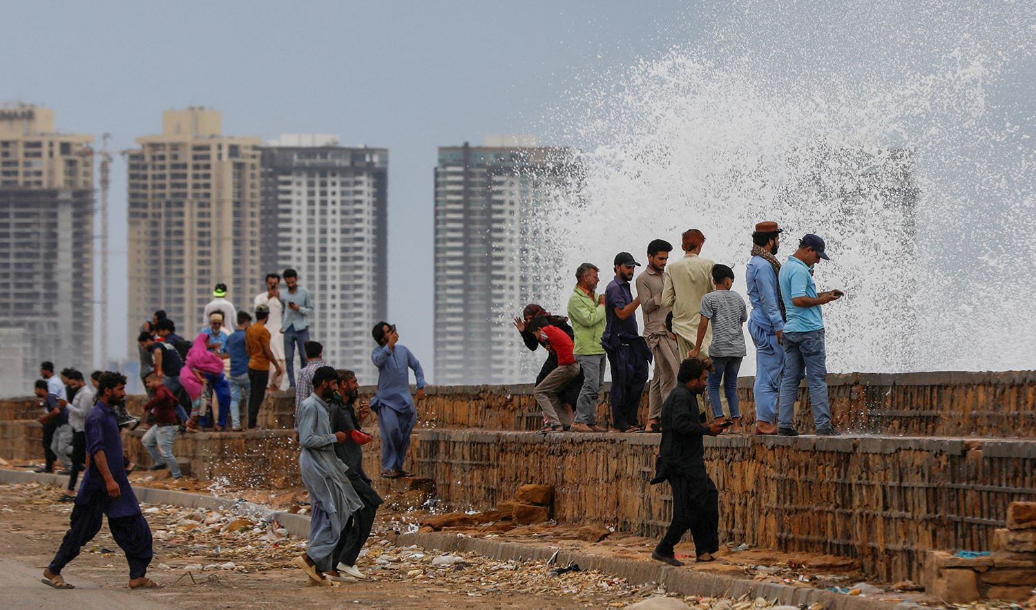 People gather near the rising waves, before the arrival of the cyclonic storm, Biparjoy, over the Arabian Sea, at Clifton Beach, in Karachi, on June 13, 2023. (REUTERS)