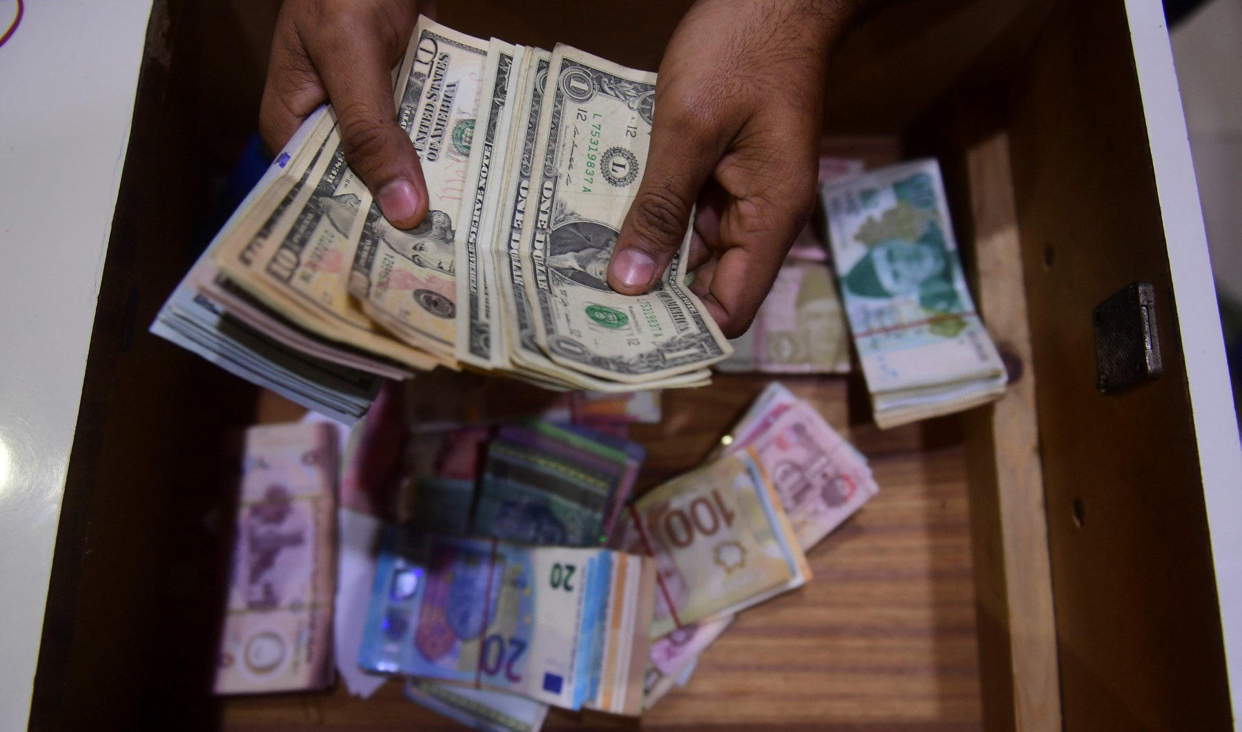 A dealer counts US dollars at a money exchange market in Karachi on January 27, 2023. (AFP/File)