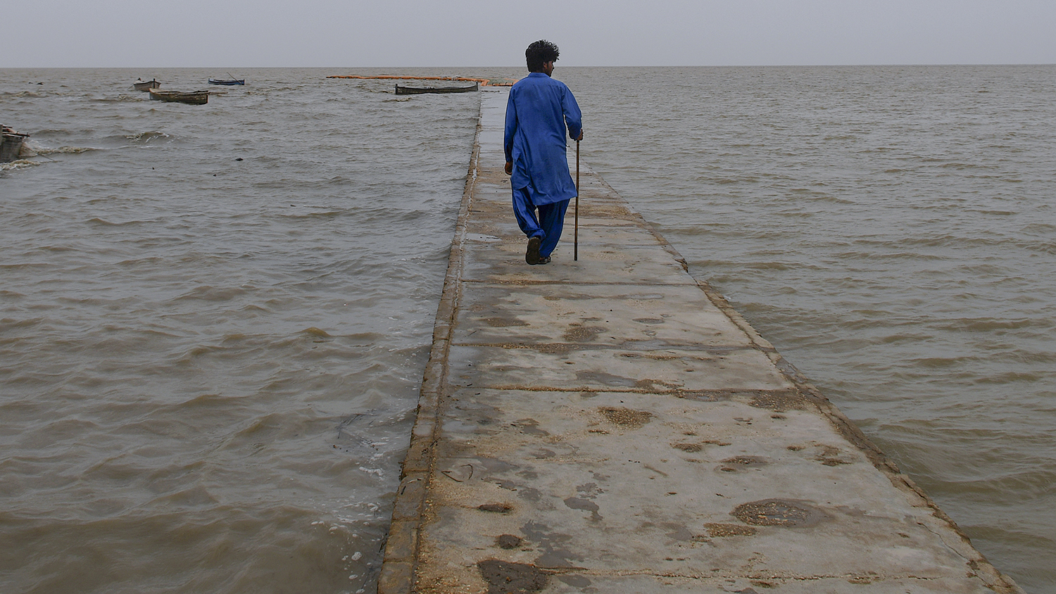 A man walks on a floating pathway on a Sea coast, which looks empty after people evacuated due to Cyclone Biparjoy approaching, in Golarchi near Badin, Pakistan's southern district in the Sindh province, Wednesday, June 14, 2023. (AP)