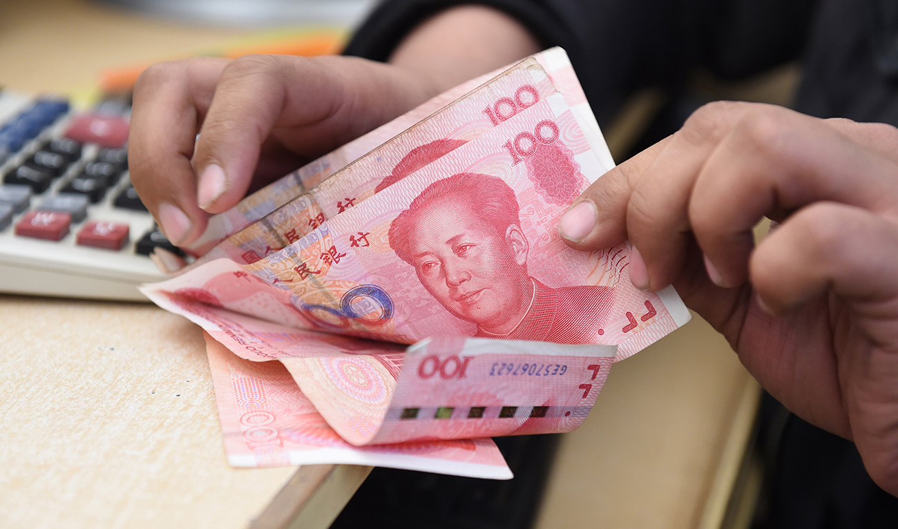 A Pakistani currency dealer counts Chinese currency for his customer at his shop in Quetta on January 3, 2018. (AFP/File)