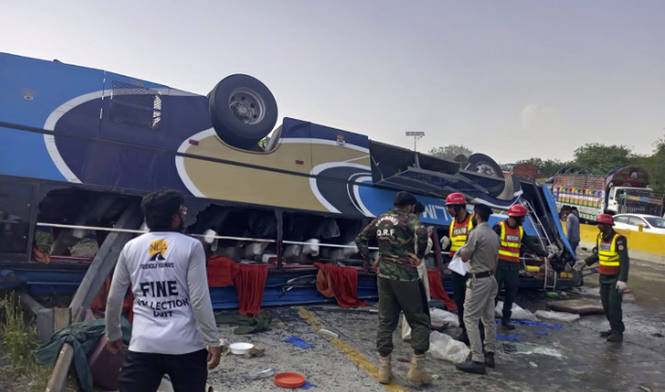 Police and rescue workers stand in front of the accident site after a passenger bus crash near the Kalar Kahar area of Pakistan's Punjab province on June 17, 2023. (Photo courtesy: National Highways & Motorway Police)