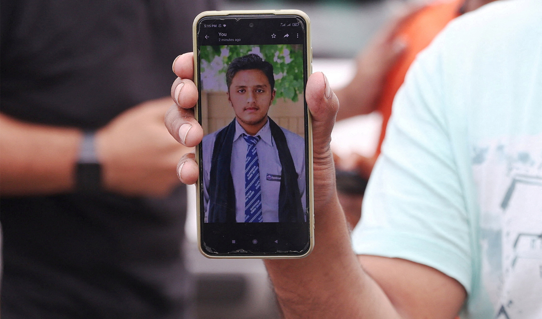 Pakistani Hassan Ali, who says his brother Fahad, 21, was onboard a boat with migrants that capsized at open sea off Greece, shows a photo of his brother in front of a migrant camp in Malakasa, near Athens, Greece, on June 16, 2023. (REUTERS)