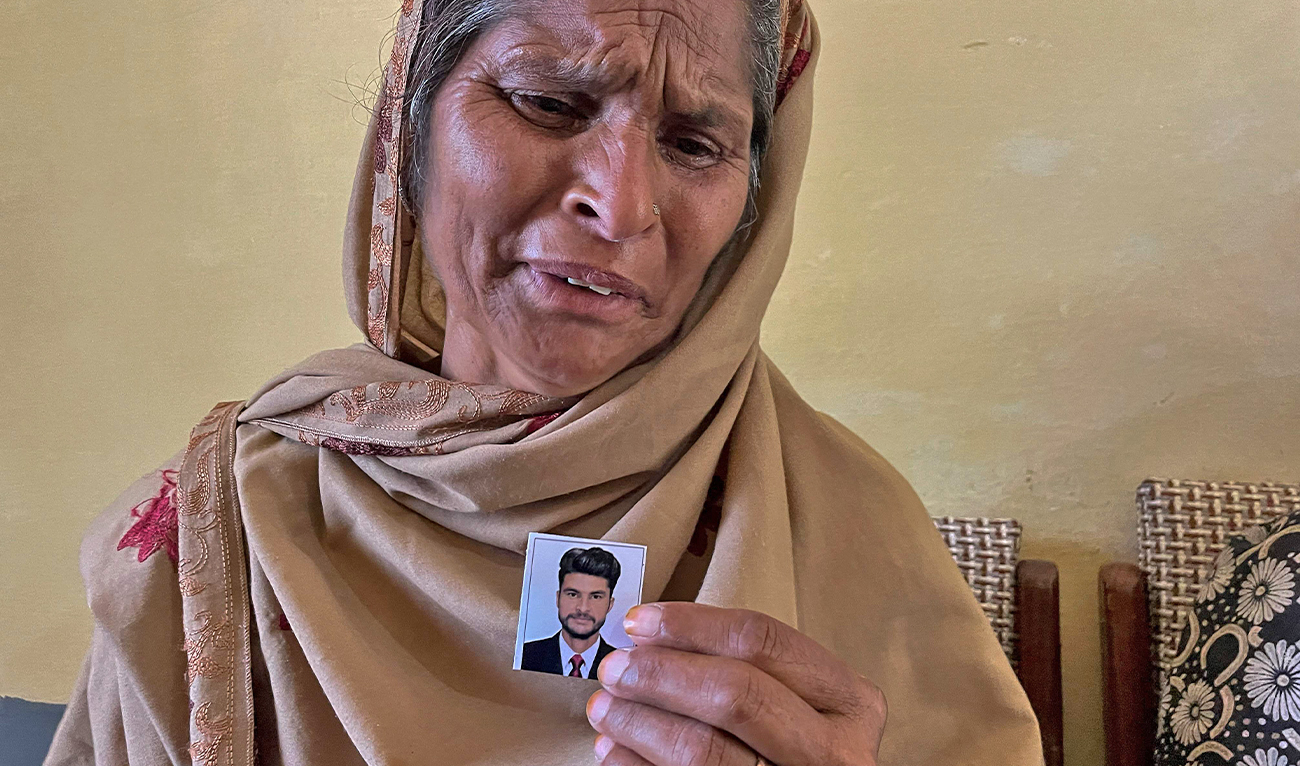In this picture taken on June 20, 2023, Tazeem Pervaiz, mother of migrant Taquir Pervaiz who is missing after an overloaded trawler capsized and sank in the Ionian Sea, weeps while holding a picture of her son in Bandli village, in Pakistan-administered Kashmir. (AFP)
