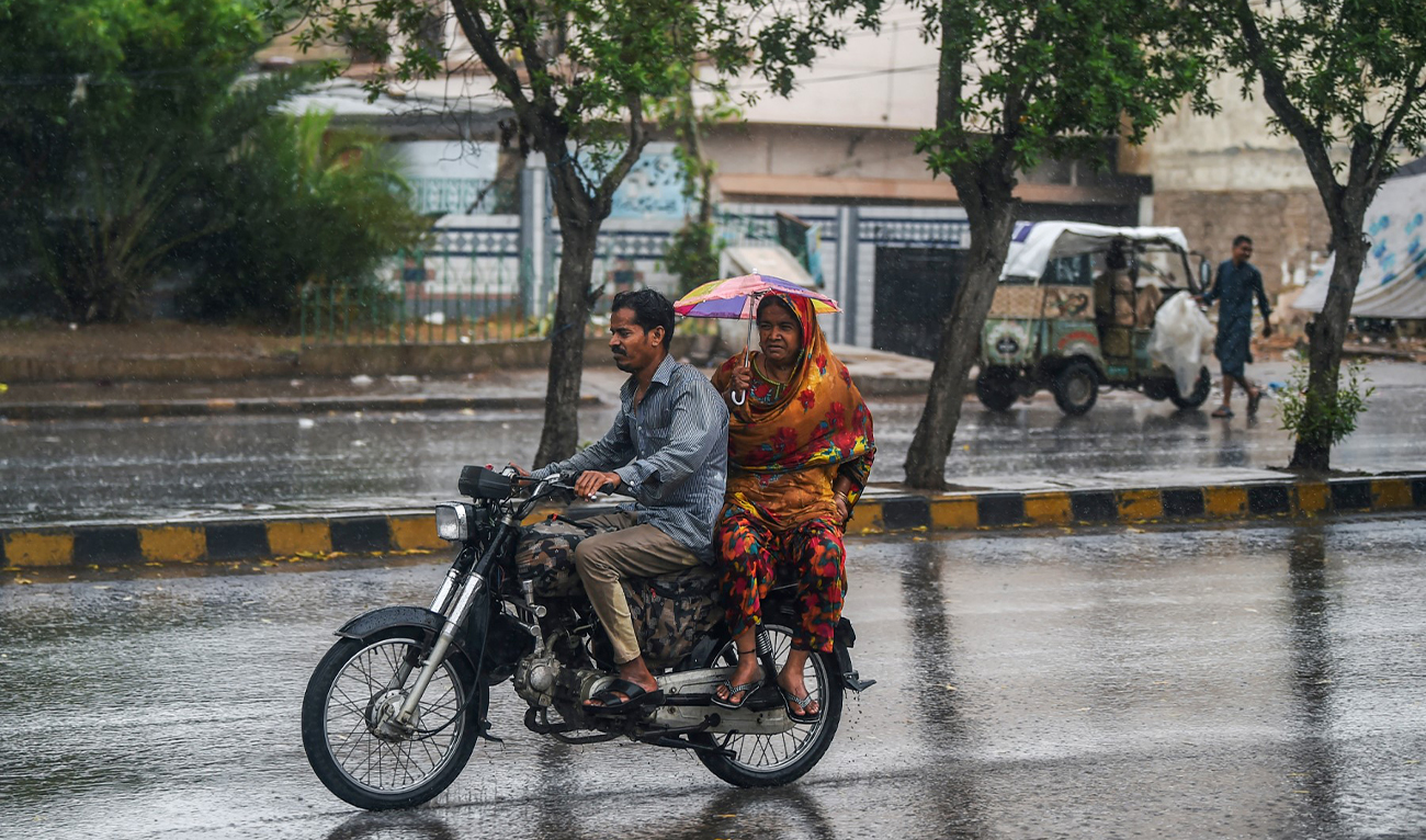 Commuters make their way amid rain showers in Karachi, Pakistan, on June 15, 2023. (AFP/File)