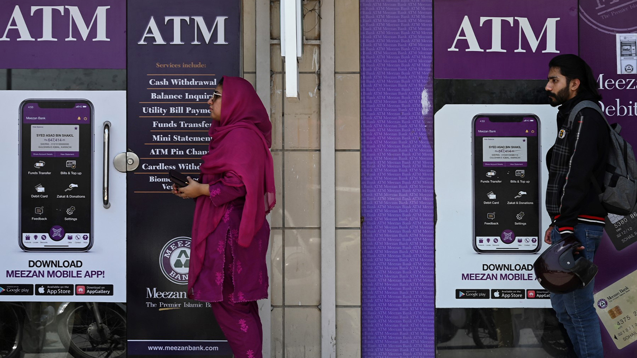 People queue along a street to use an ATM bank machine in Rawalpindi on June 9, 2023. (AFP/File)
