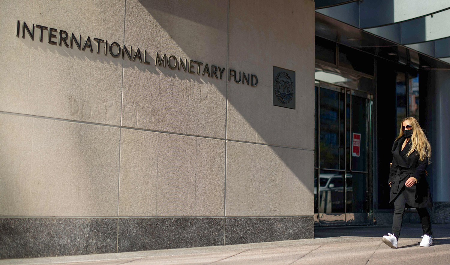 A woman passing by International Monetary Fund (IMF) headquarters in Washington DC, United States on April 5, 2021. (AFP/File)