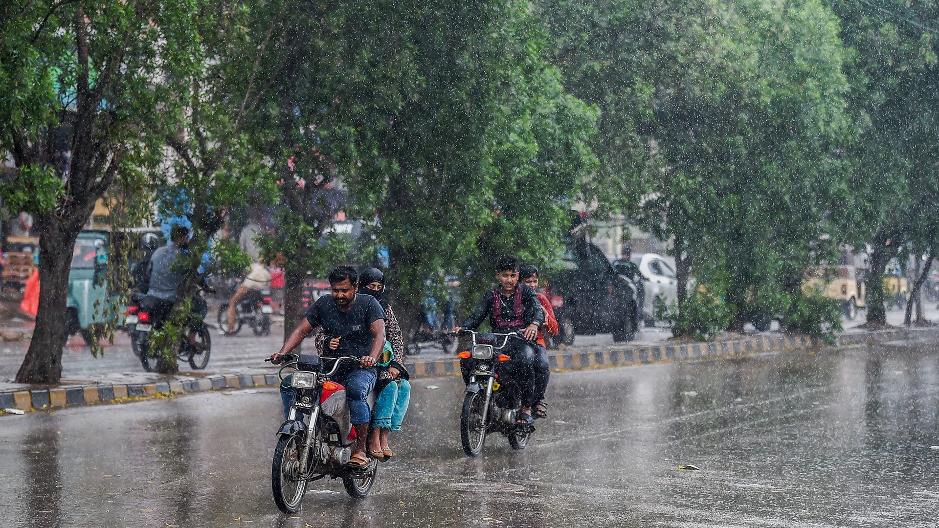 Commuters make their way amid rain showers in Karachi on June 15, 2023. (AFP/File)