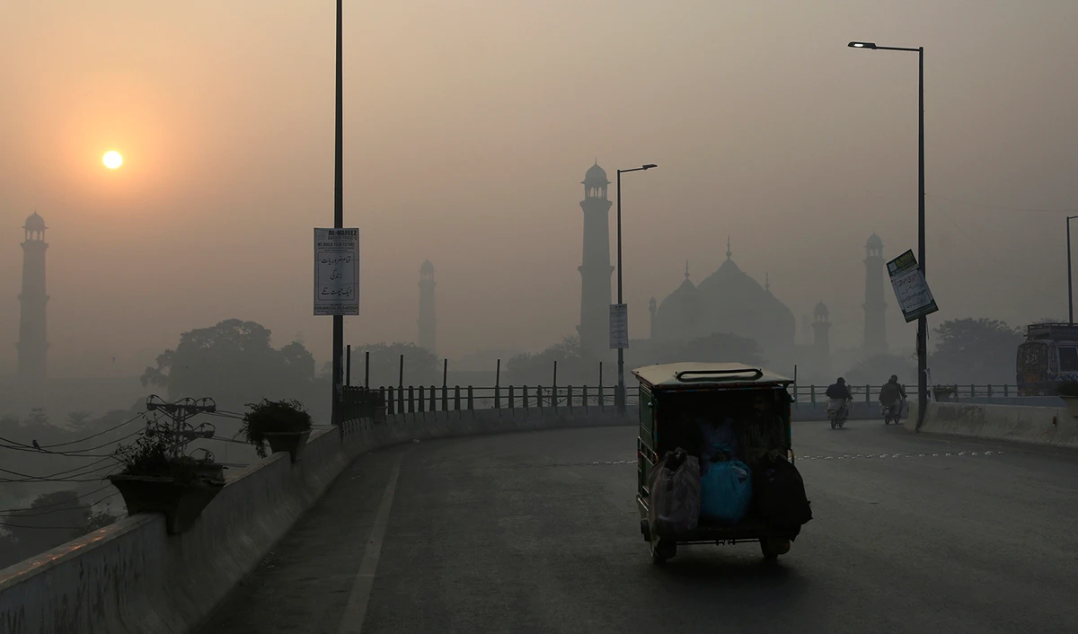 An auto rickshaw moves on a road as smog envelops the historical Badshahi mosque and the surrounding area of Lahore, Pakistan, on November 27, 2021. (AP/File)