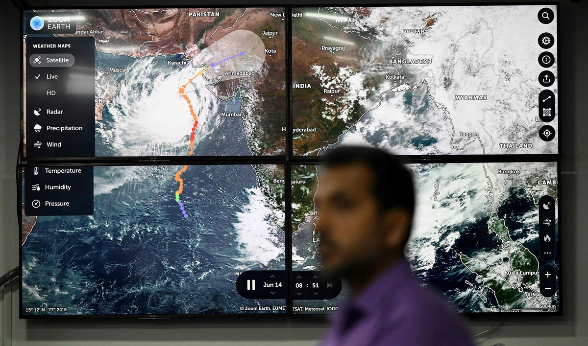 An official of the National Disaster Management Authority (NDMA) stands in front of a TV screen displaying satellite images of cyclone Biparjoy at the NDMA monitoring room in Islamabad, Pakistan, on June 14, 2023. (AFP)